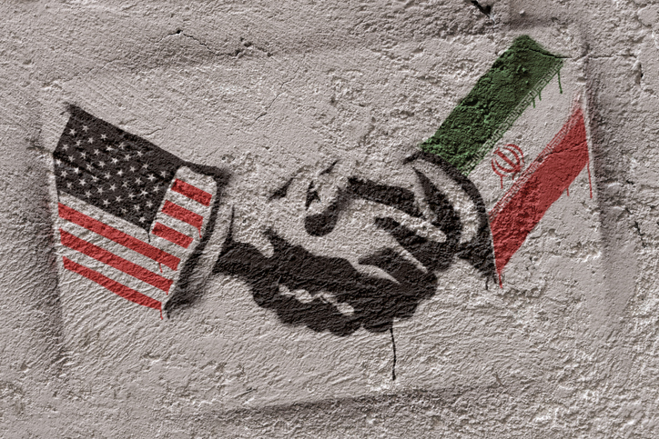 Handshake graffiti with U.S. and Iran flags symbolizing Iran‑US MOU and potential sanctions relief.